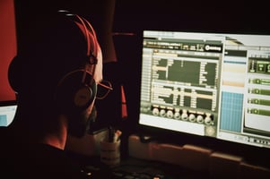 Image of a music producer looking at their computer screen making edits to their song