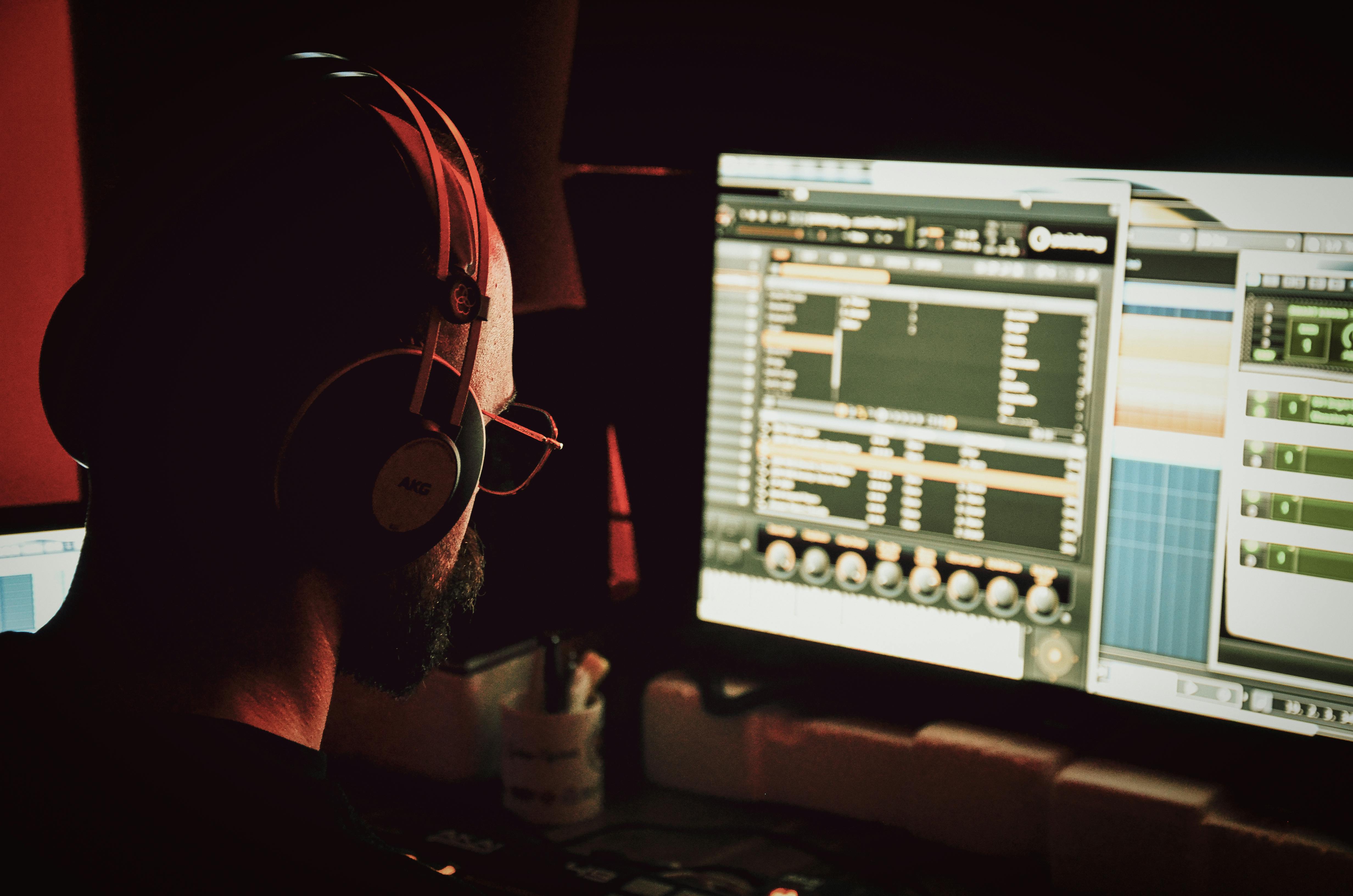 Image of a music producer looking at their computer screen making edits to their song